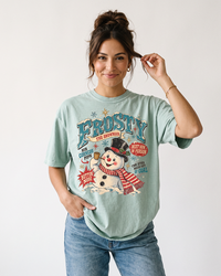 Woman wearing a Bay green Frosty the Snowman vintage Christmas heavyweight graphic tee with oversized retro holiday artwork and blue jeans.