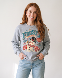 Woman with long auburn hair wearing a Sport Grey Frosty the Snowman vintage Christmas crewneck sweatshirt with light blue jeans.