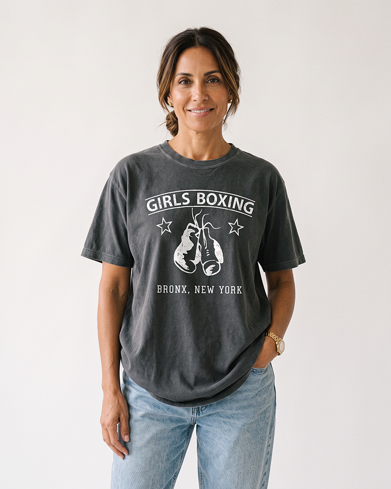 Brunette woman wearing a Pepper gray Girls Boxing heavyweight graphic tee with light-wash jeans.