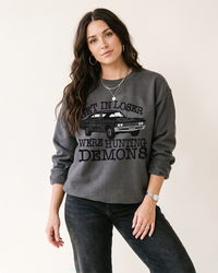 Charcoal Get In Loser We're Hunting Demons graphic sweatshirt on female model
