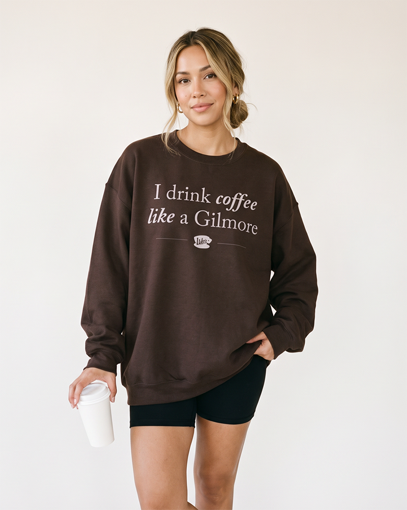 Woman holding coffee while wearing dark chocolate I Drink Coffee Like a Gilmore crewneck sweatshirt