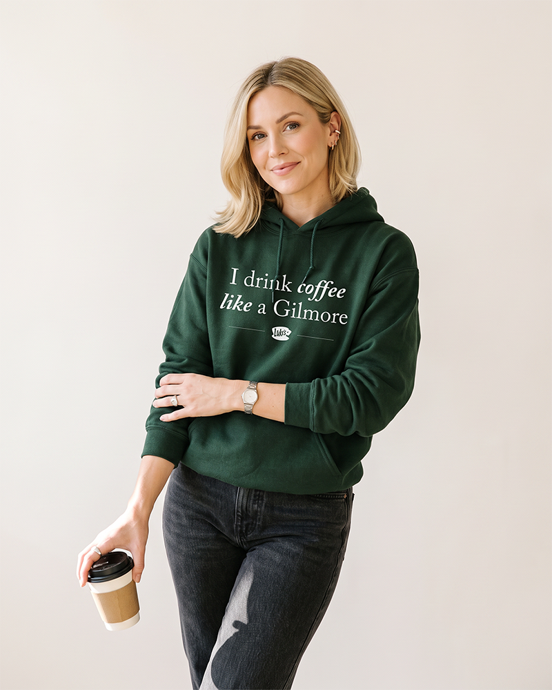Woman wearing forest green I Drink Coffee Like a Gilmore hoodie inspired by Gilmore Girls and Luke's Diner