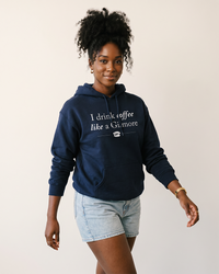 Woman wearing navy I Drink Coffee Like a Gilmore graphic hoodie inspired by Gilmore Girls and Stars Hollow