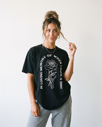 Woman wearing black In Loving Memory heavyweight graphic tee featuring skeleton hand and rose artwork