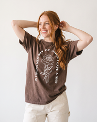 Red-haired woman wearing Espresso In Loving Memory heavyweight graphic tee with skeleton hand and rose design