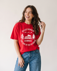 Woman wearing red Jolliest Bunch of Assholes heavyweight Christmas tee
