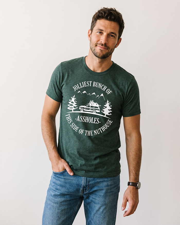 Man wearing forest green Jolliest Bunch of Assholes Christmas tee