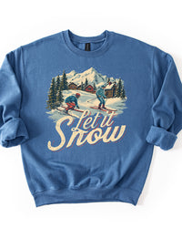 Indigo blue midweight crewneck sweatshirt featuring vintage skiers, snowy mountain village illustration and distressed Let It Snow lettering.