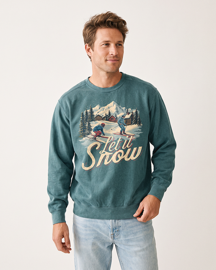 Man wearing a Blue Spruce Let It Snow vintage ski sweatshirt with retro alpine winter graphic and light wash jeans.
