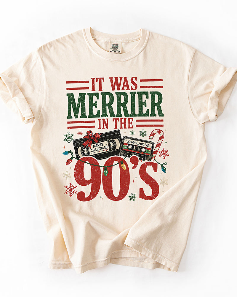 Ivory Comfort Colors heavyweight Christmas tee featuring It Was Merrier in the 90s lettering, vintage holiday cassette tapes, and colorful Christmas lights.