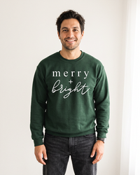 Man wearing forest green Merry + Bright Christmas crewneck sweatshirt