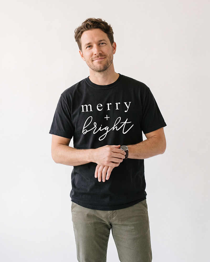 Man wearing black Merry + Bright heavyweight Christmas graphic tee