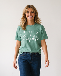 Woman wearing light green Merry + Bright heavyweight holiday t-shirt