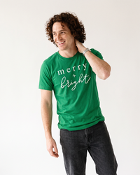 Man wearing Kelly green Merry + Bright Christmas graphic t-shirt