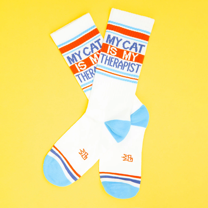 My Cat Is My Therapist cotton gym socks arranged in a crossed flat lay with blue and orange accents