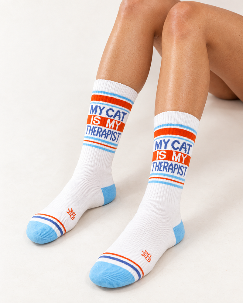 Close-up of My Cat Is My Therapist novelty socks modeled with blue lettering and orange accents