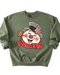 Military Green Christmas crewneck sweatshirt featuring a large distressed retro snowman with red scarf, pipe, and flowered top hat.