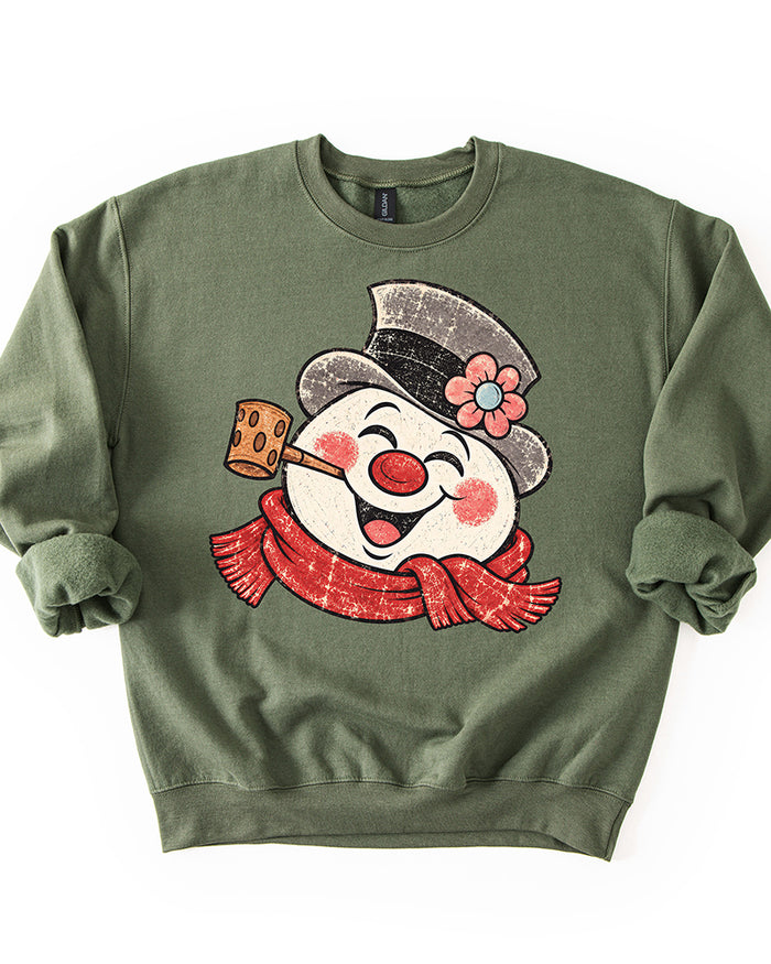 Military Green Christmas crewneck sweatshirt featuring a large distressed retro snowman with red scarf, pipe, and flowered top hat.