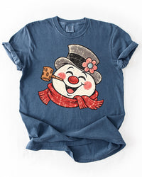 Denim blue Comfort Colors heavyweight tee featuring a large smiling retro snowman Christmas graphic.