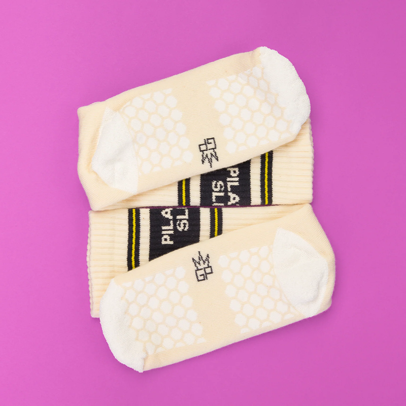 Close-up of woven-in honeycomb grip pattern on bottom of ivory Pilates Slut socks