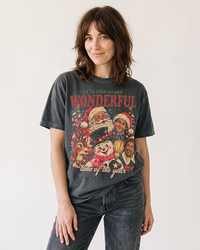 Brunette woman wearing a Pepper gray vintage Christmas graphic tee with holiday character collage and dark jeans.