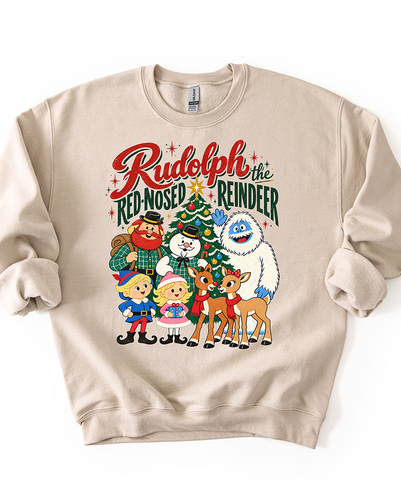 Sand crewneck Christmas sweatshirt featuring vintage Rudolph the Red-Nosed Reindeer characters, retro holiday lettering, and a decorated Christmas tree.