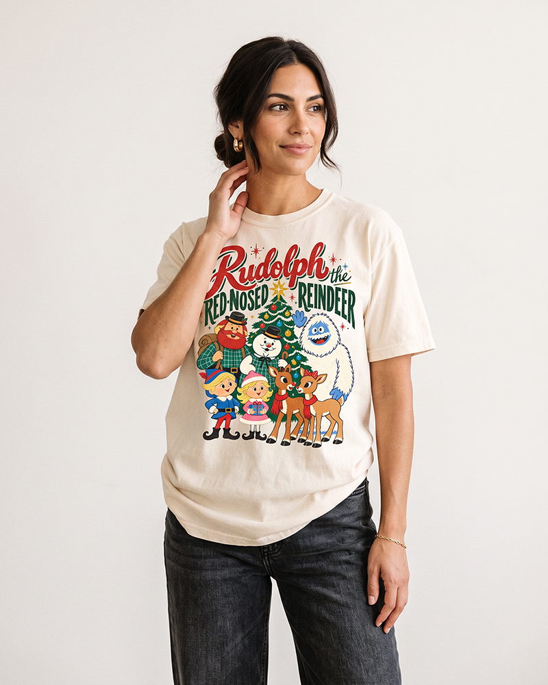 Woman with dark hair wearing an Ivory Rudolph vintage Christmas heavyweight graphic tee with black jeans, featuring classic holiday characters.