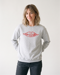 Blonde woman modeling an ash gray Save The Drama For Your Mama crewneck sweatshirt with dark jeans.