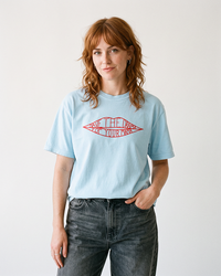 Red-haired woman wearing a chambray blue Save The Drama For Your Mama heavyweight graphic tee with dark washed jeans.