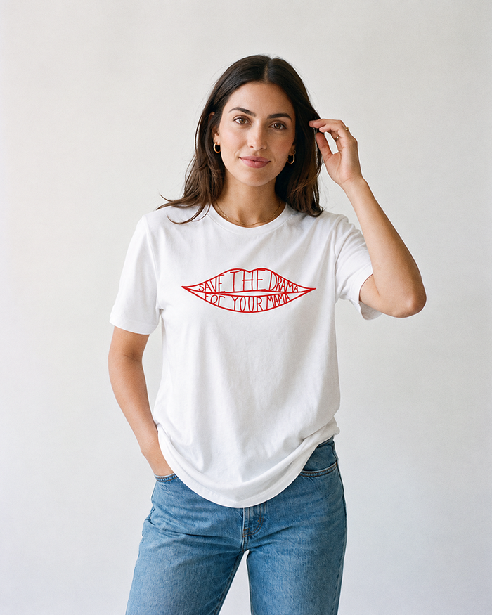 Woman modeling white Save The Drama For Your Mama lightweight graphic tee with red lips design and blue jeans.