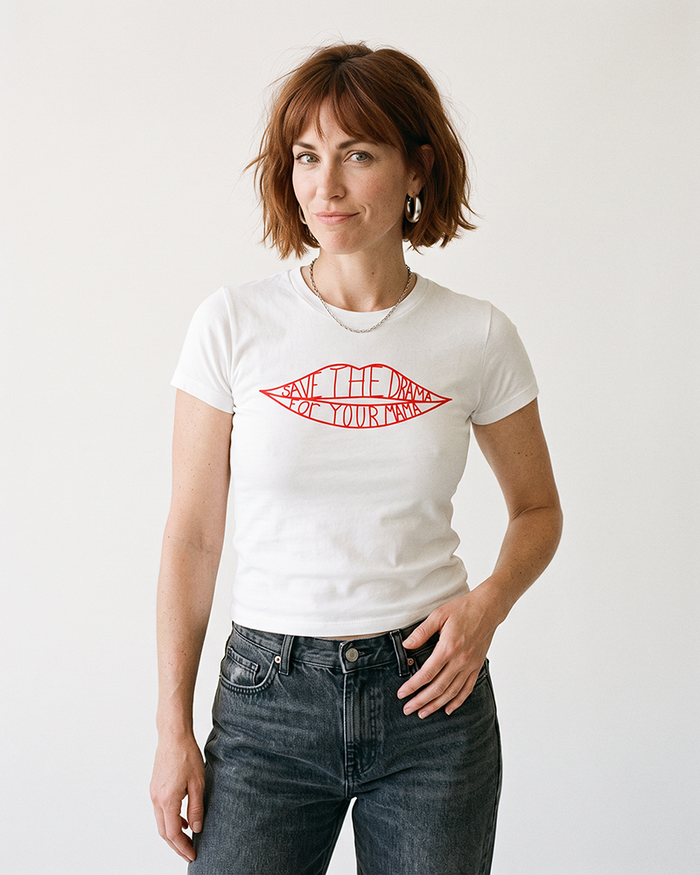 Woman modeling a fitted white Save The Drama For Your Mama baby tee with dark wash jeans.