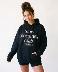 Woman wearing black Slow Mornings Club graphic hoodie