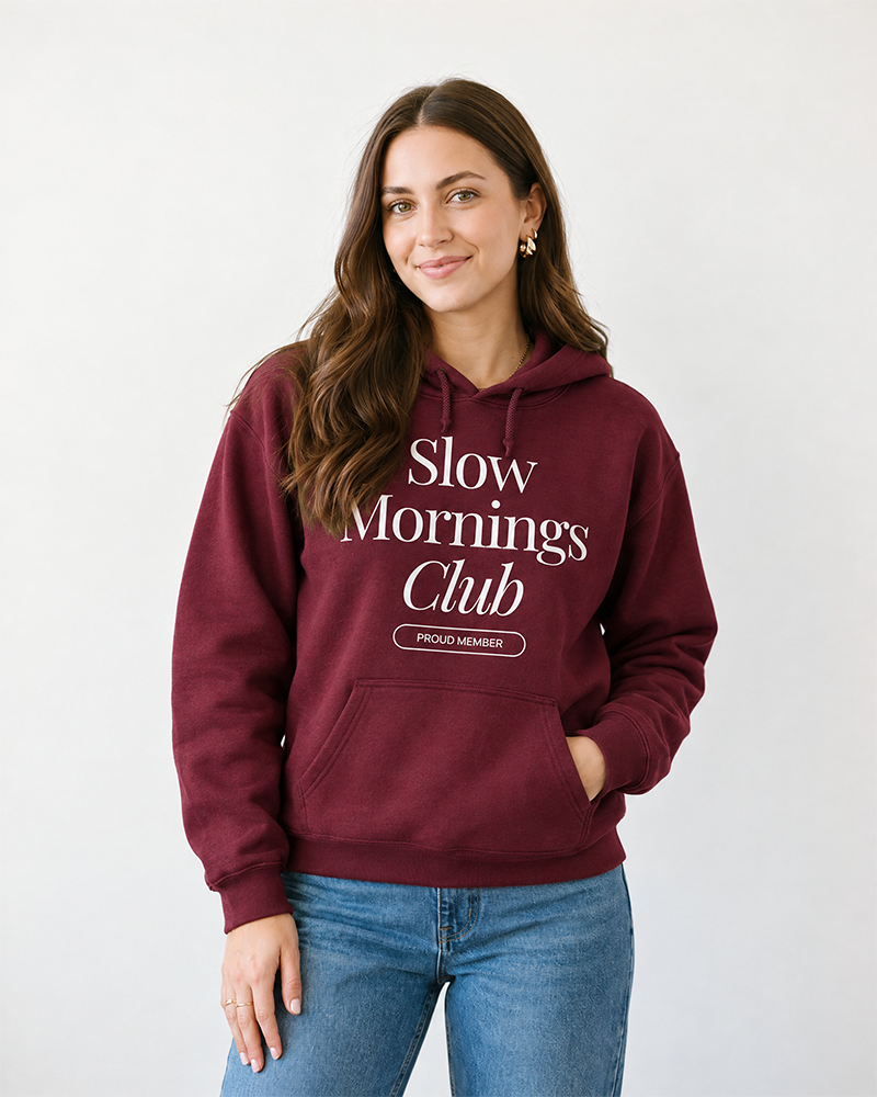 Woman wearing maroon Slow Mornings Club graphic hoodie