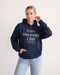 Woman wearing navy Slow Mornings Club graphic hoodie