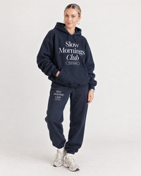 Woman wearing navy Slow Mornings Club hoodie and matching sweatpants