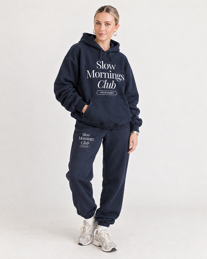 Woman wearing navy Slow Mornings Club hoodie and matching sweatpants