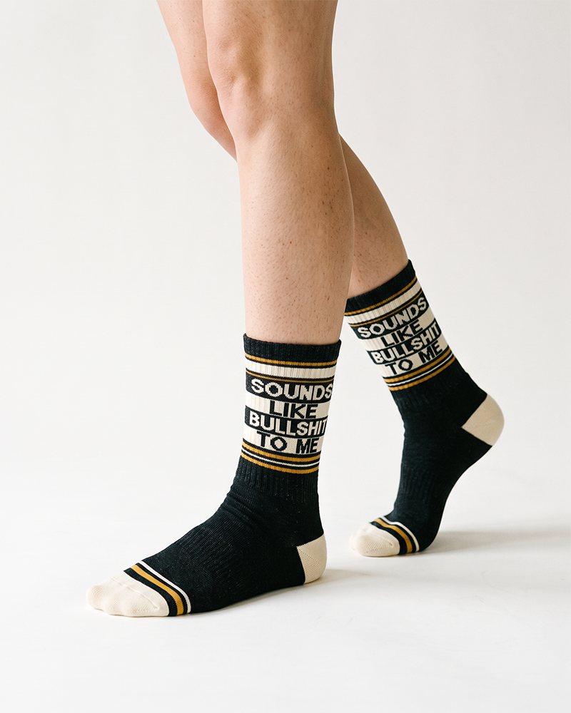 Close-up of black novelty crew socks featuring Sounds Like Bullshit To Me lettering and cream toes