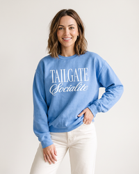 Woman wearing light blue Tailgate Socialite crewneck sweatshirt with white graphic, casual football sweatshirt