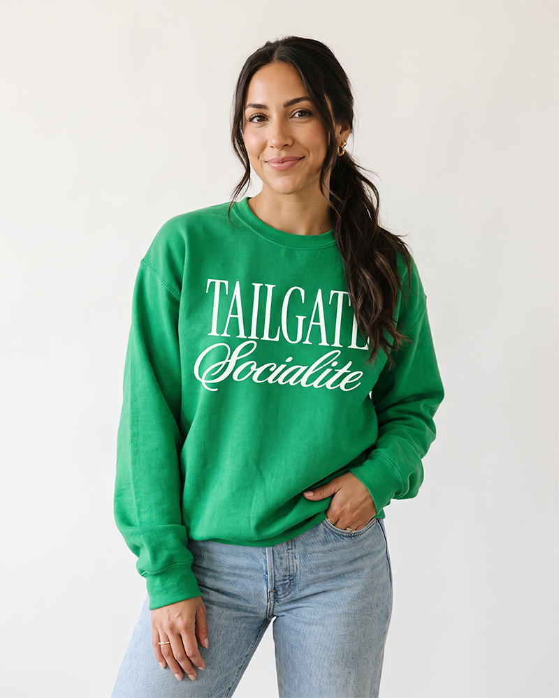 Woman wearing green Tailgate Socialite crewneck sweatshirt with white graphic, game day apparel