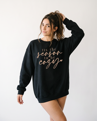 Woman wearing oversized black Tis the Season to Be Cozy crewneck sweatshirt