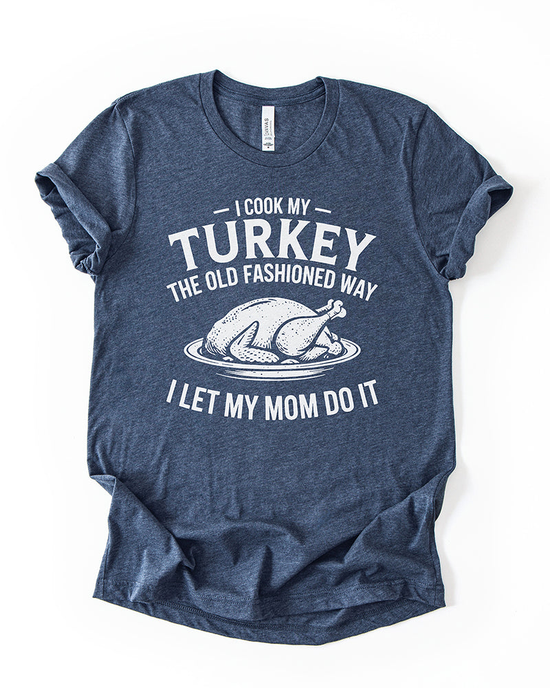Heather Navy funny Thanksgiving lightweight tee featuring white lettering that reads I Cook My Turkey the Old Fashioned Way I Let My Mom Do It.